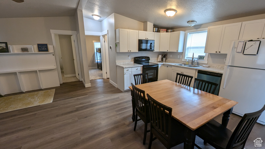 Kitchen with white cabinets, black appliances, sink, and vaulted ceiling