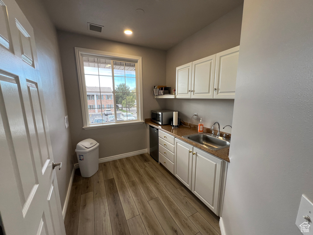 Kitchen with light wood-type flooring, sink, and white cabinets