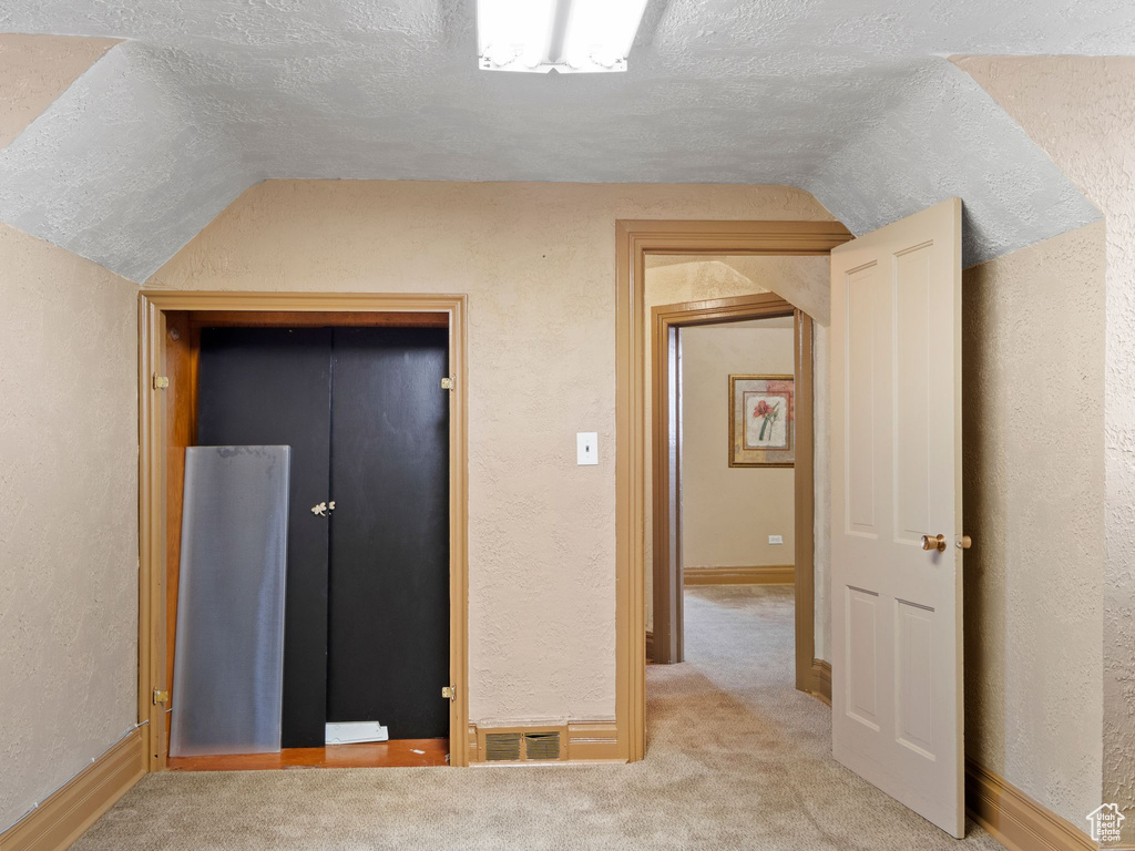 Interior space featuring a textured ceiling, carpet flooring, a closet, and lofted ceiling