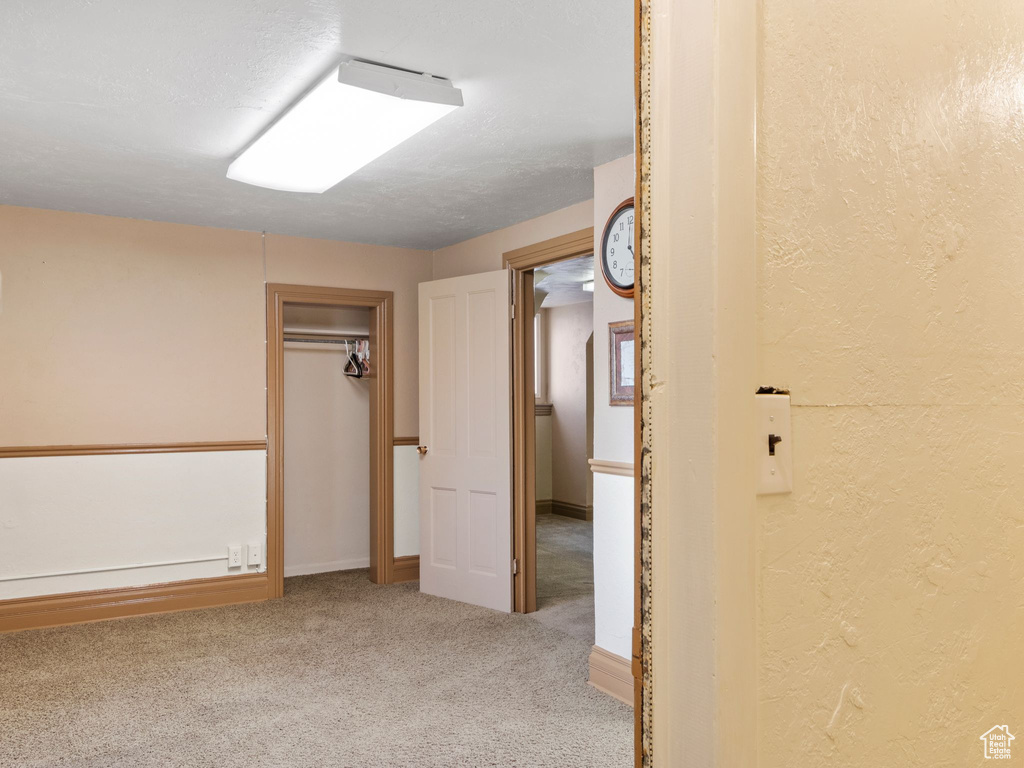 Unfurnished bedroom featuring light colored carpet, a textured ceiling, and a closet