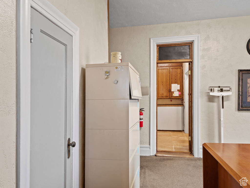 Corridor featuring a textured ceiling and light carpet