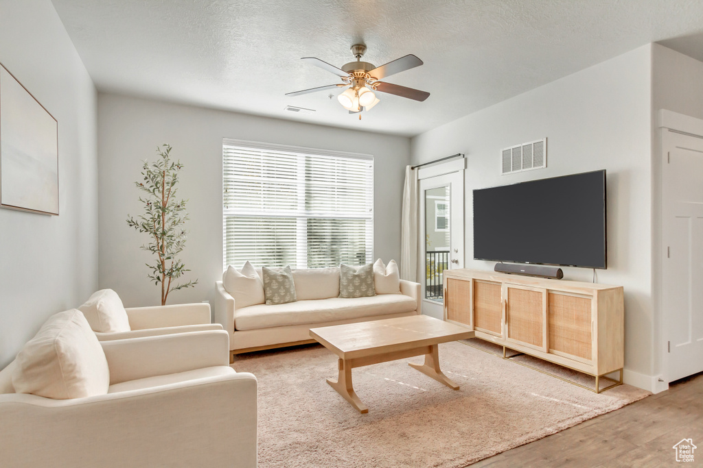 Living room featuring hardwood / wood-style floors, ceiling fan, and a textured ceiling