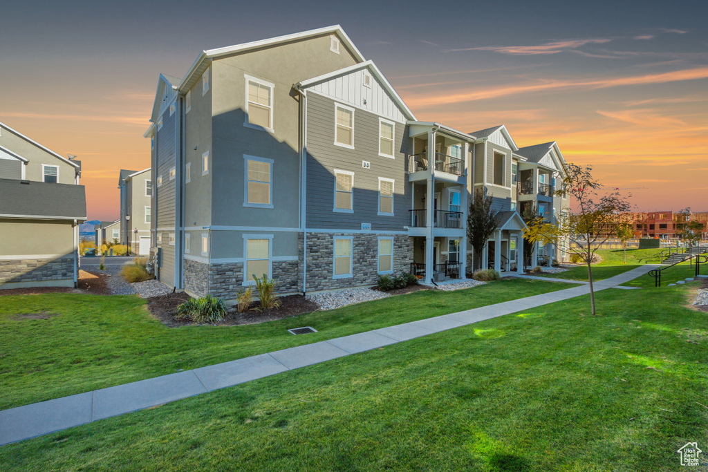 View of front of house featuring a balcony and a yard