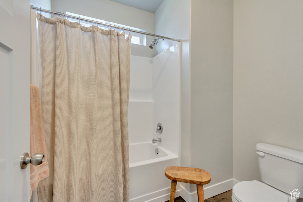 Bathroom featuring hardwood / wood-style flooring, toilet, and shower / tub combo