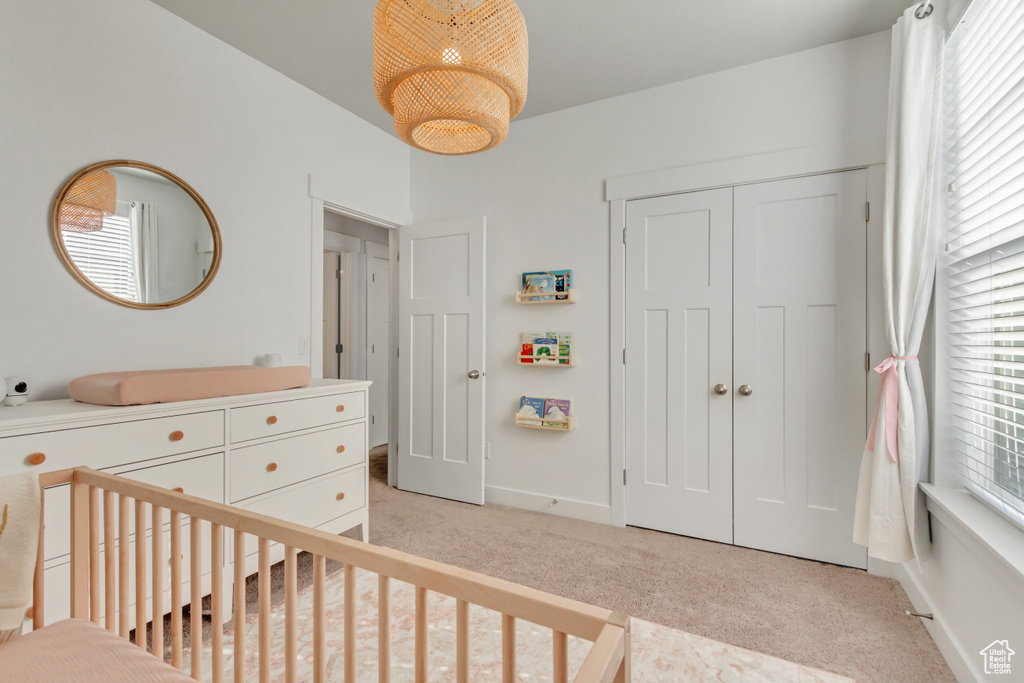 Bedroom with a closet, light carpet, a nursery area, and multiple windows