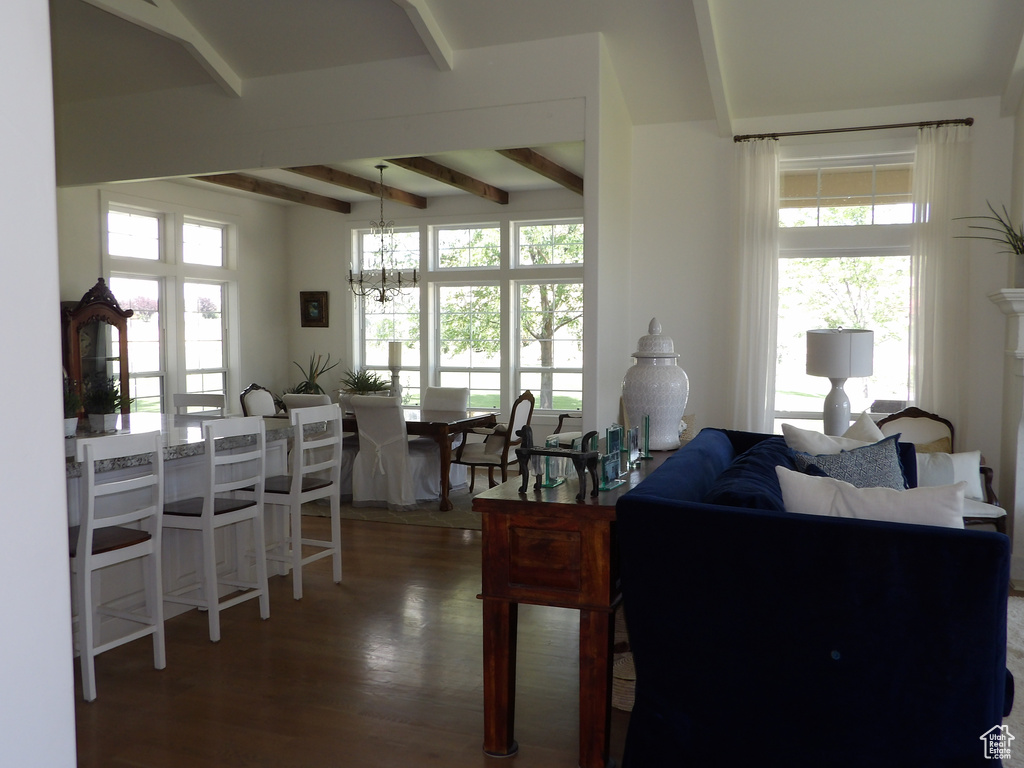 Living room featuring dark hardwood / wood-style flooring, beamed ceiling, and a chandelier