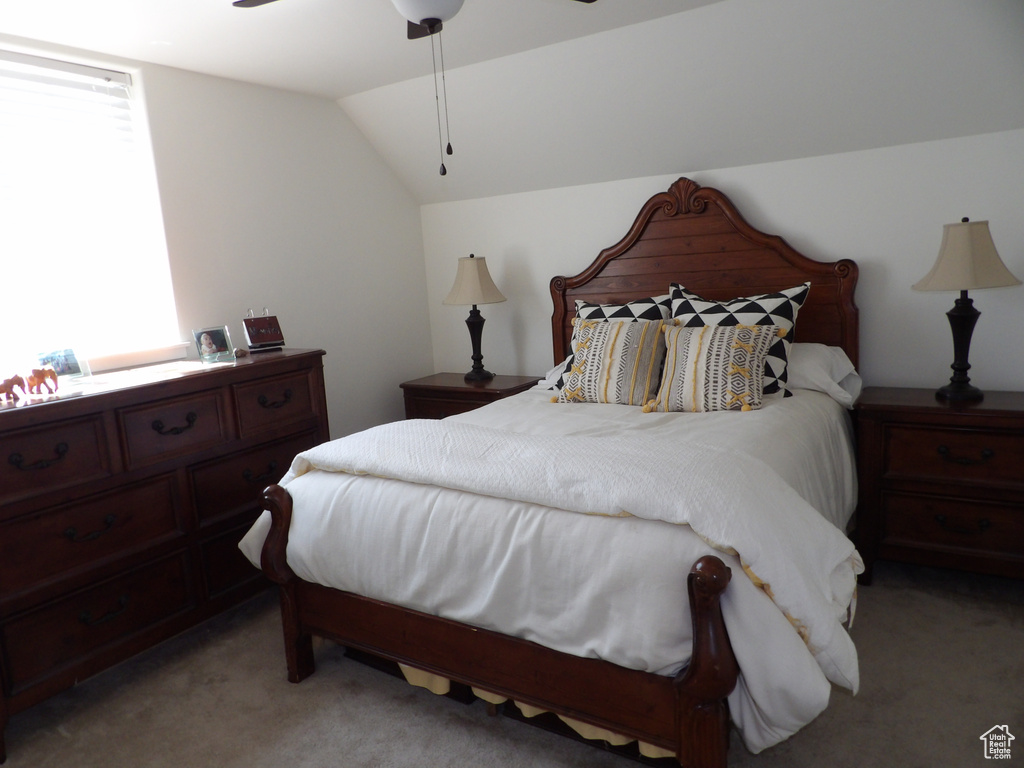 Carpeted bedroom with ceiling fan and vaulted ceiling