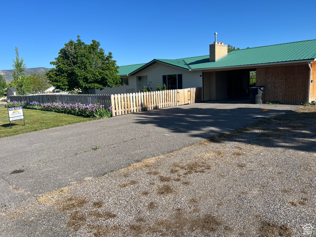 View of front of property with a chimney, asphalt driveway, metal roof, and an attached carport