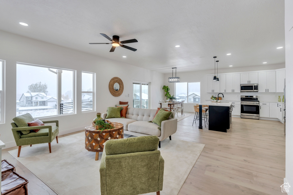 Living room featuring ceiling fan, sink, and light hardwood / wood-style flooring