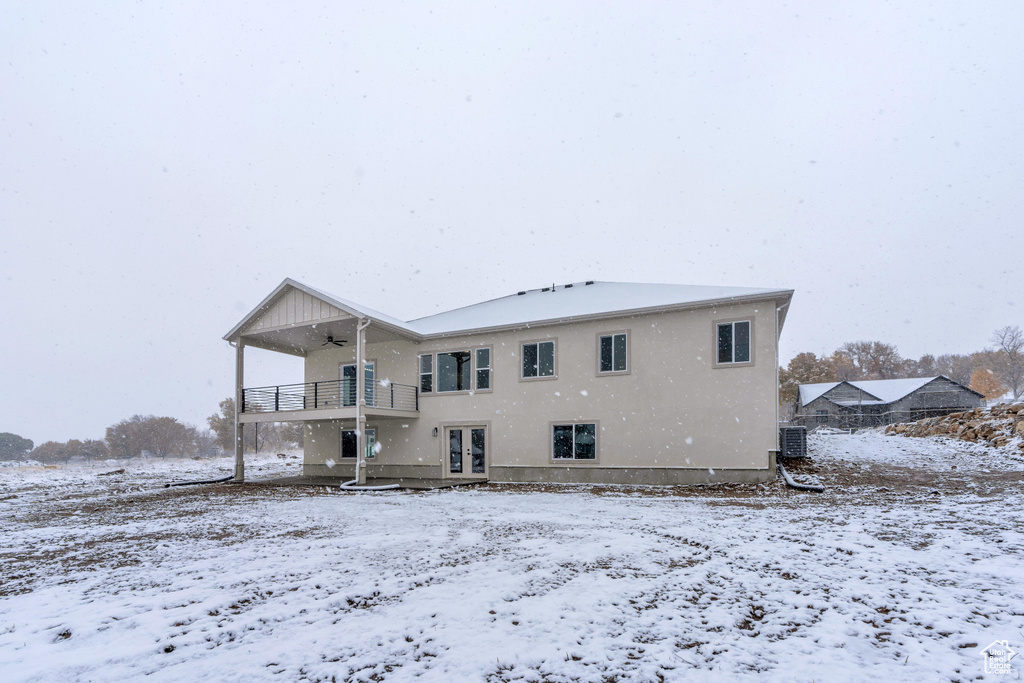 Snow covered property featuring a balcony and central AC unit