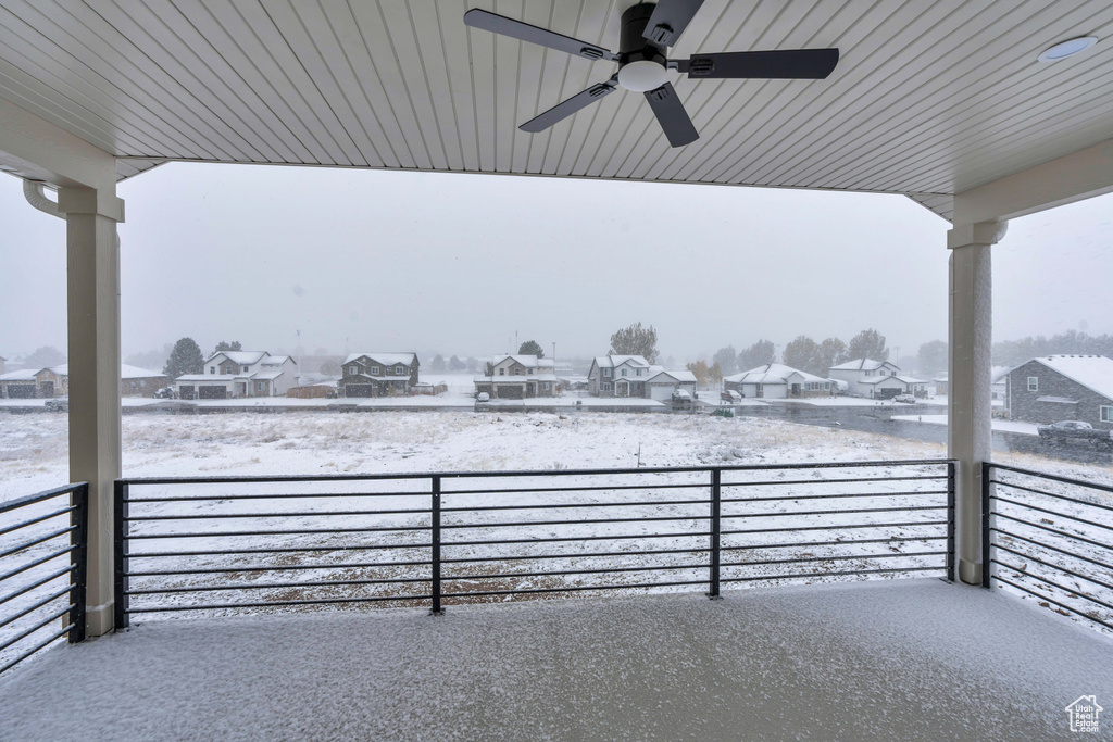 Snow covered patio featuring ceiling fan and a balcony