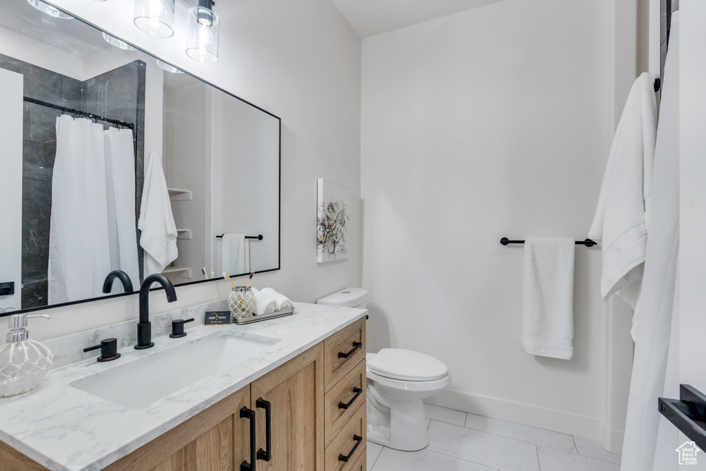 Bathroom featuring toilet, vanity, tile patterned floors, and curtained shower