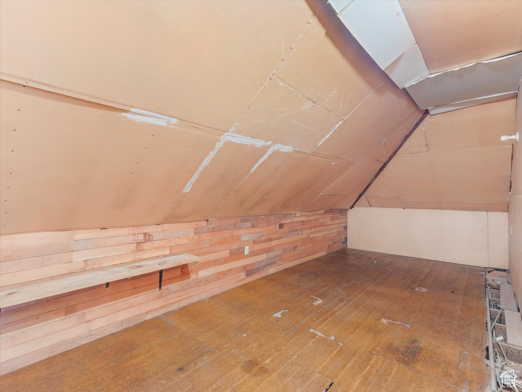 Additional living space with vaulted ceiling with skylight and hardwood / wood-style floors