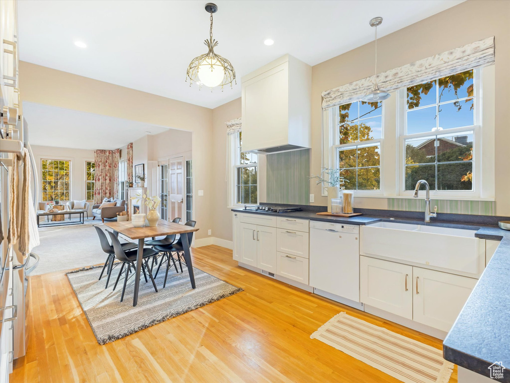 Kitchen with dishwasher, light hardwood / wood-style flooring, hanging light fixtures, and plenty of natural light