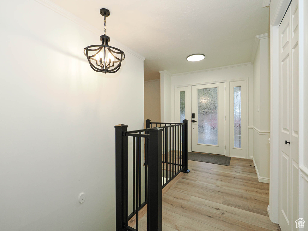 Corridor featuring light wood-type flooring, a chandelier, and crown molding