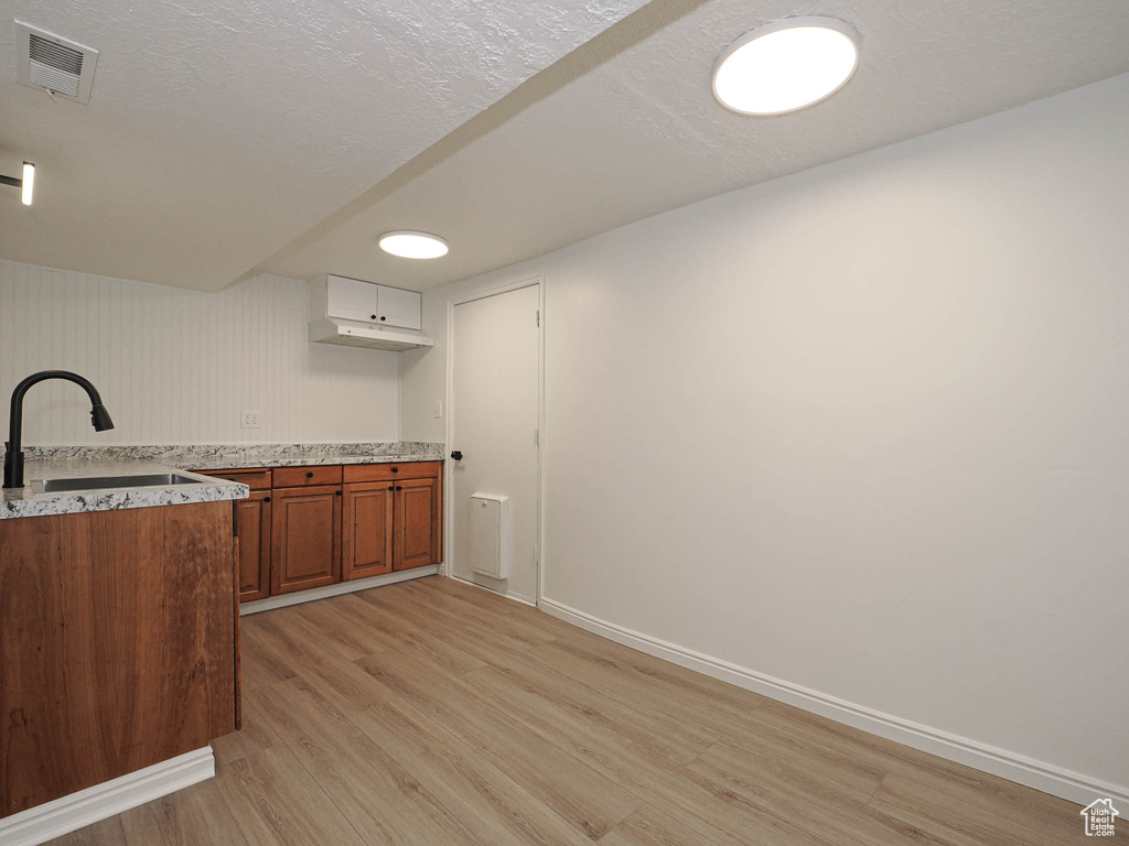 Kitchen featuring a textured ceiling, light hardwood / wood-style flooring, and sink