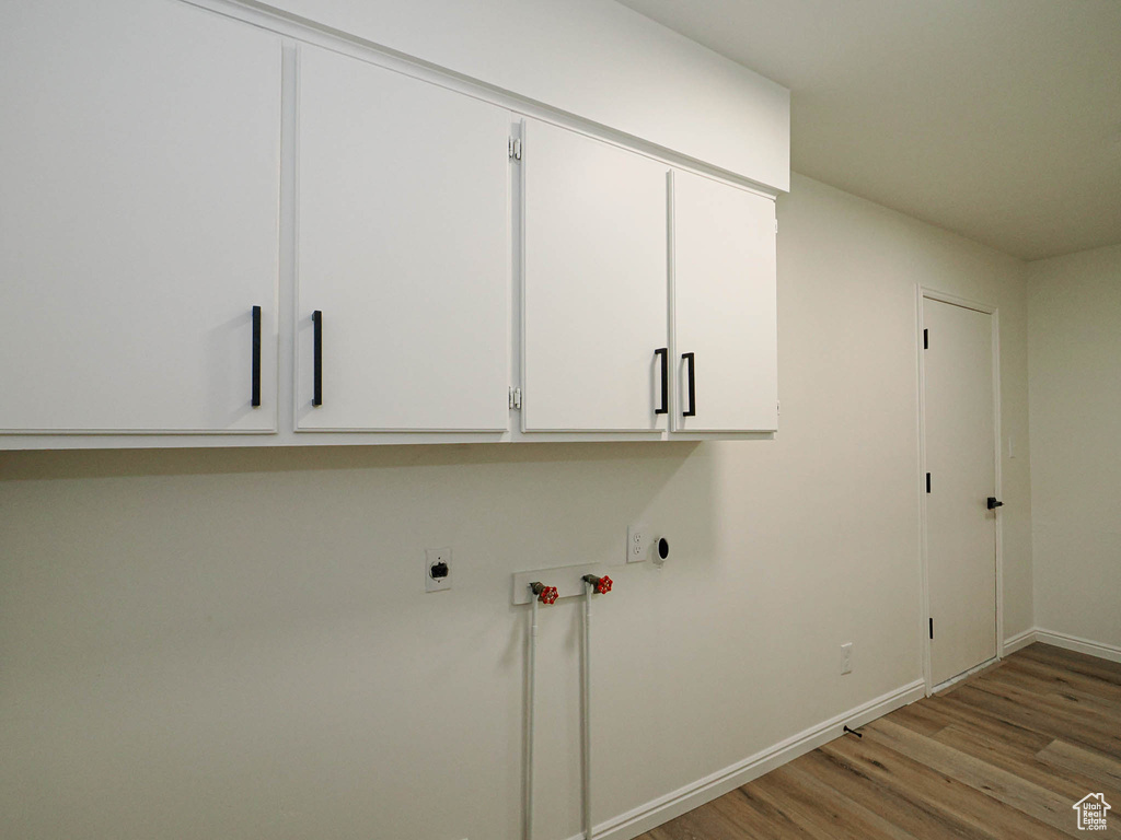 Washroom featuring cabinets, washer hookup, hookup for an electric dryer, and light hardwood / wood-style flooring