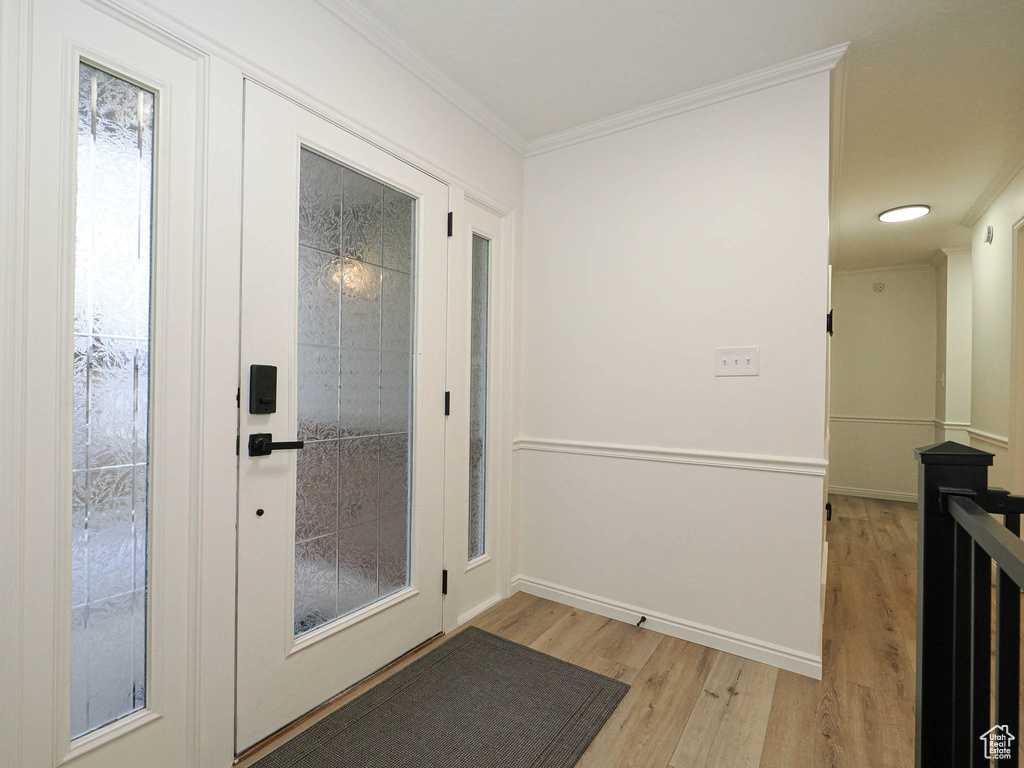 Doorway to outside with ornamental molding and light hardwood / wood-style flooring