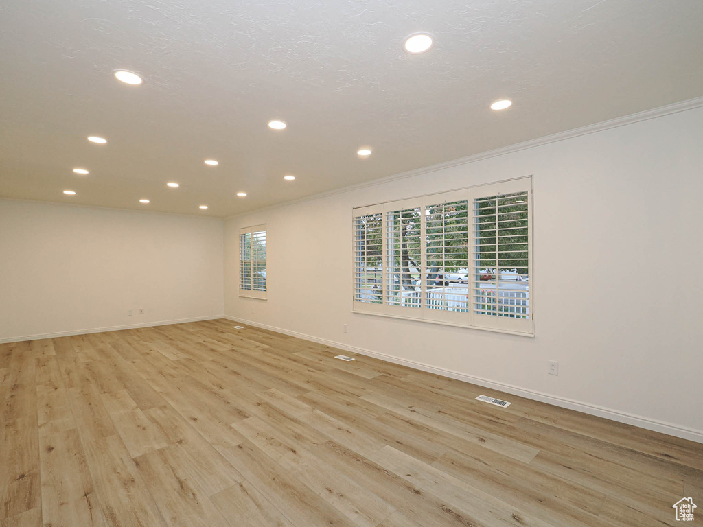 Empty room featuring light wood-type flooring and ornamental molding