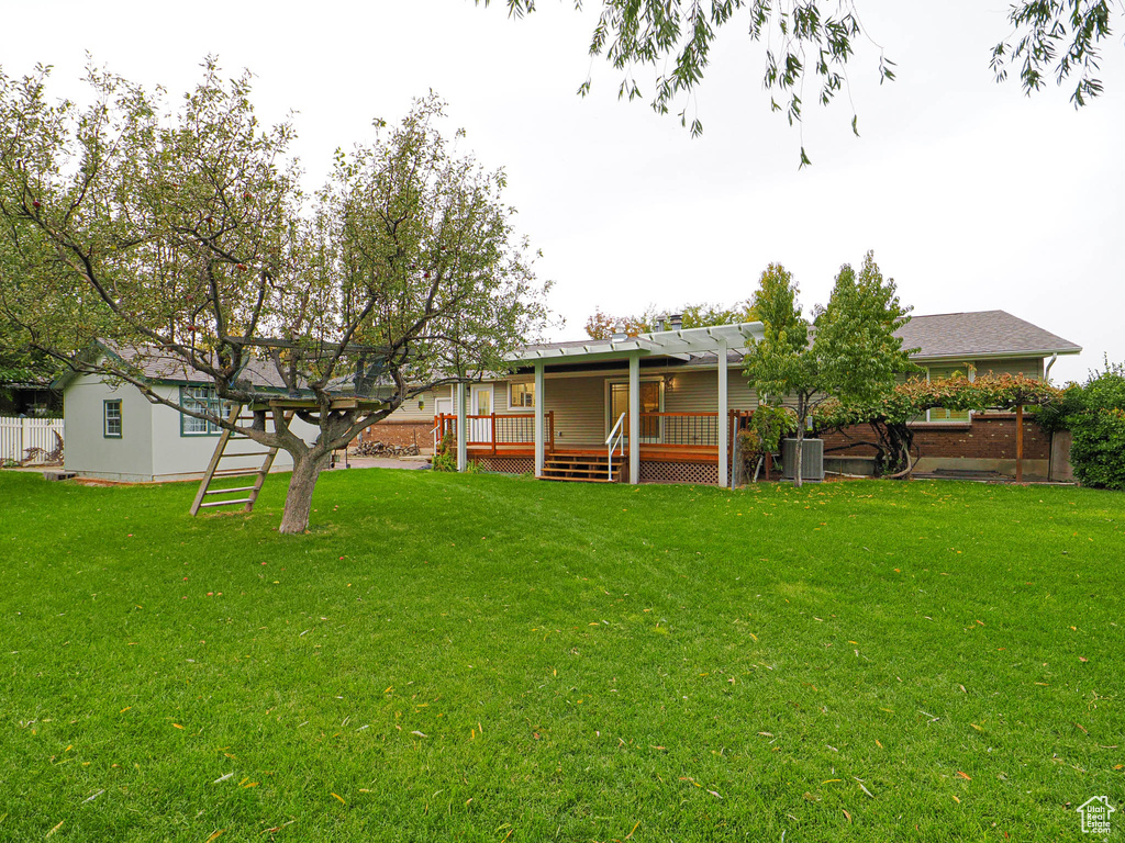 Rear view of house with a lawn and a deck