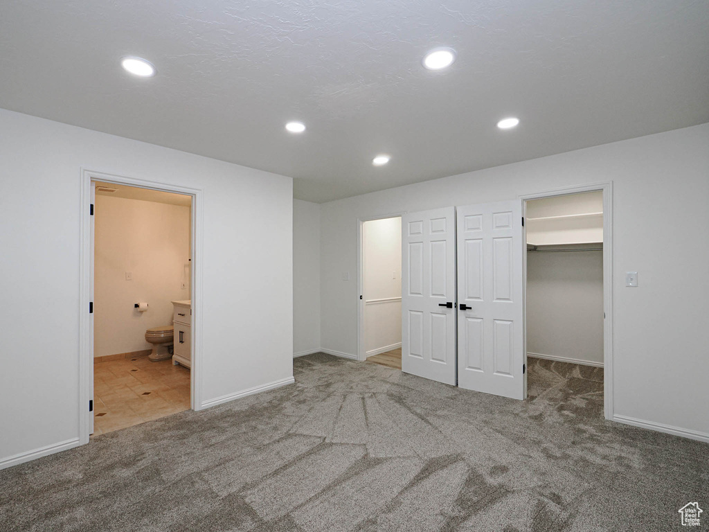 Unfurnished bedroom with a closet, a spacious closet, carpet floors, and connected bathroom