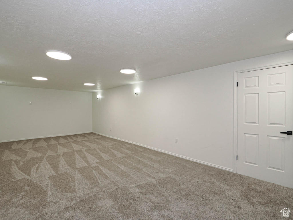 Basement featuring a textured ceiling and light carpet