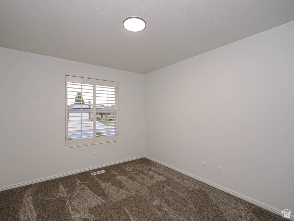 Unfurnished room featuring dark colored carpet