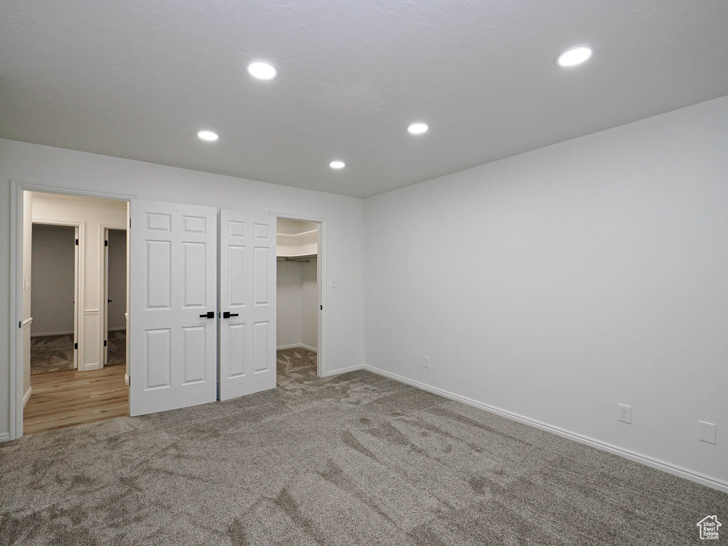 Unfurnished bedroom with a closet, a spacious closet, and carpet