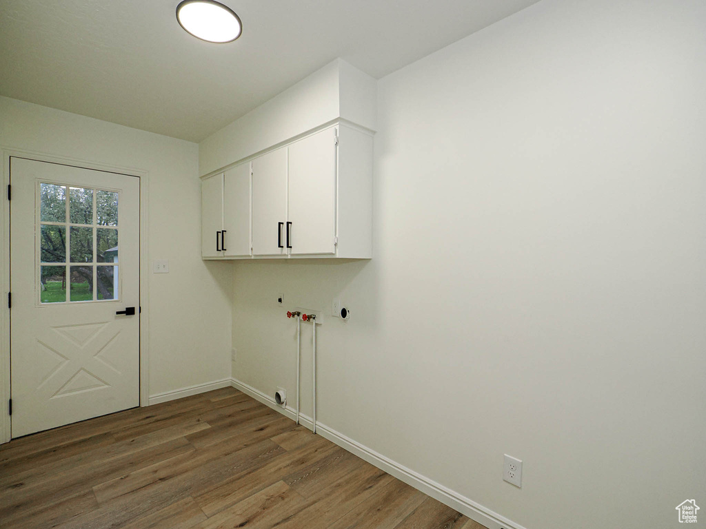 Washroom featuring cabinets, wood-type flooring, and hookup for a gas dryer