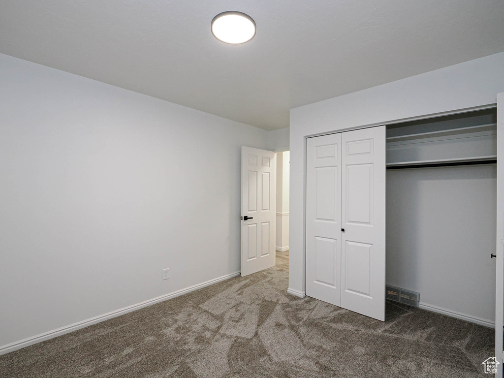 Unfurnished bedroom with dark colored carpet and a closet