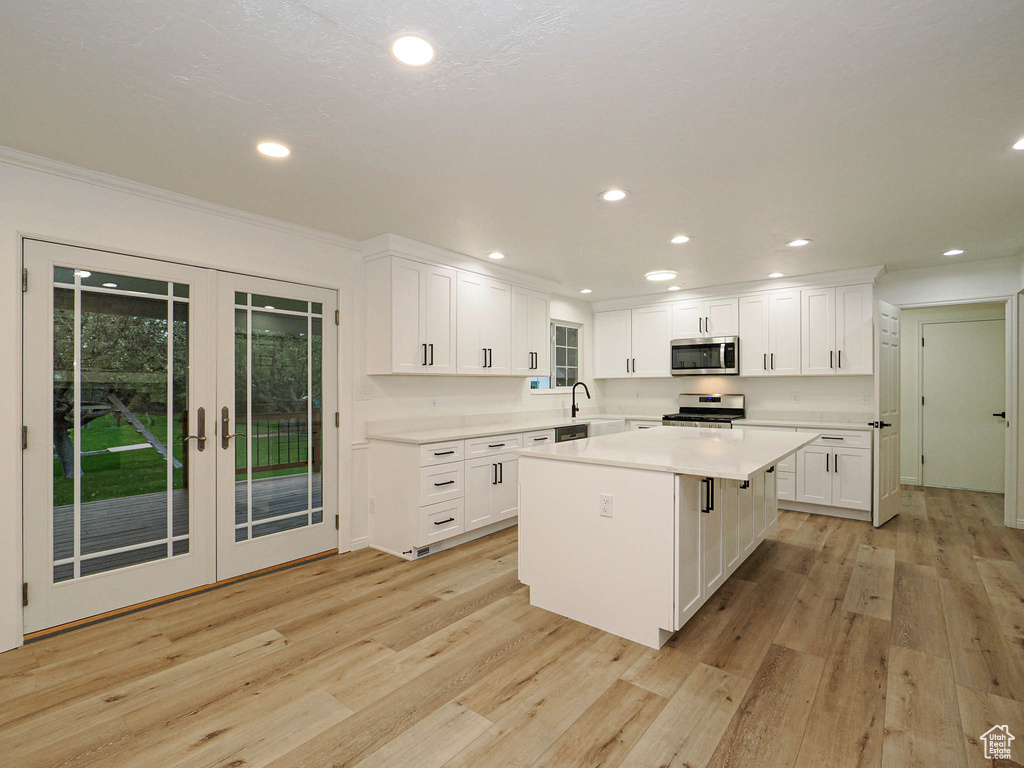 Kitchen with a kitchen island, white cabinetry, appliances with stainless steel finishes, and light hardwood / wood-style flooring