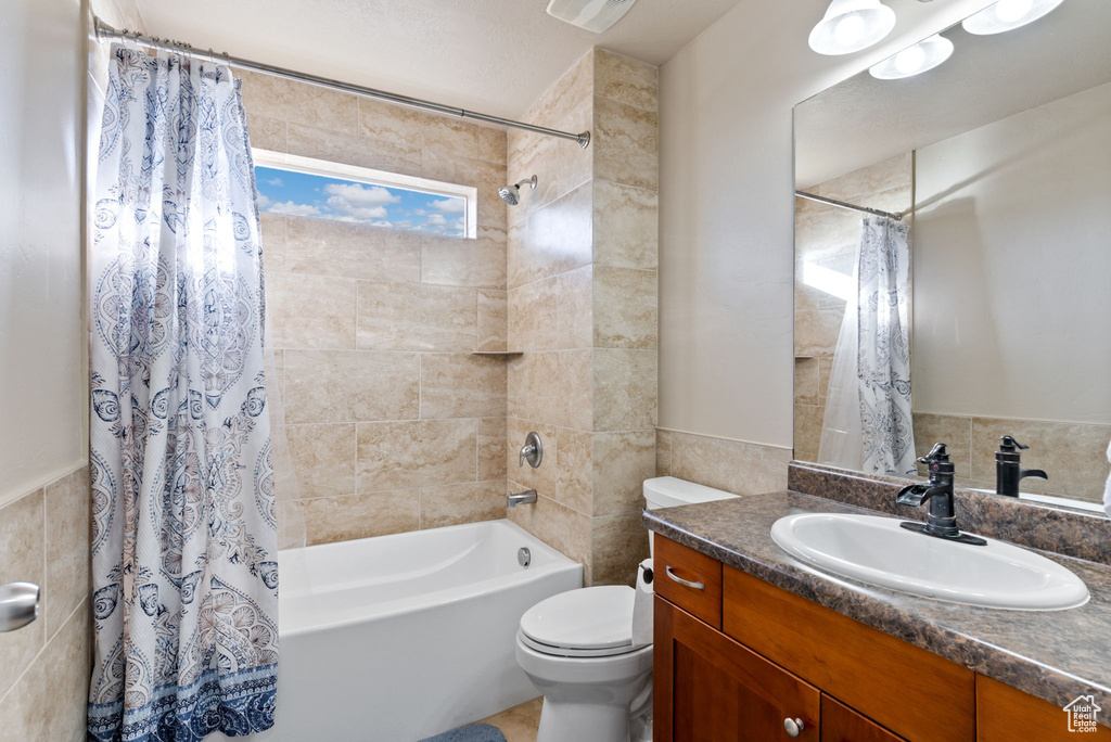 Full bathroom with shower / tub combo with curtain, vanity, toilet, and tile walls