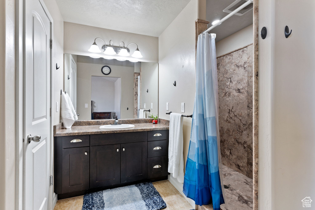 Bathroom with vanity, a textured ceiling, and curtained shower