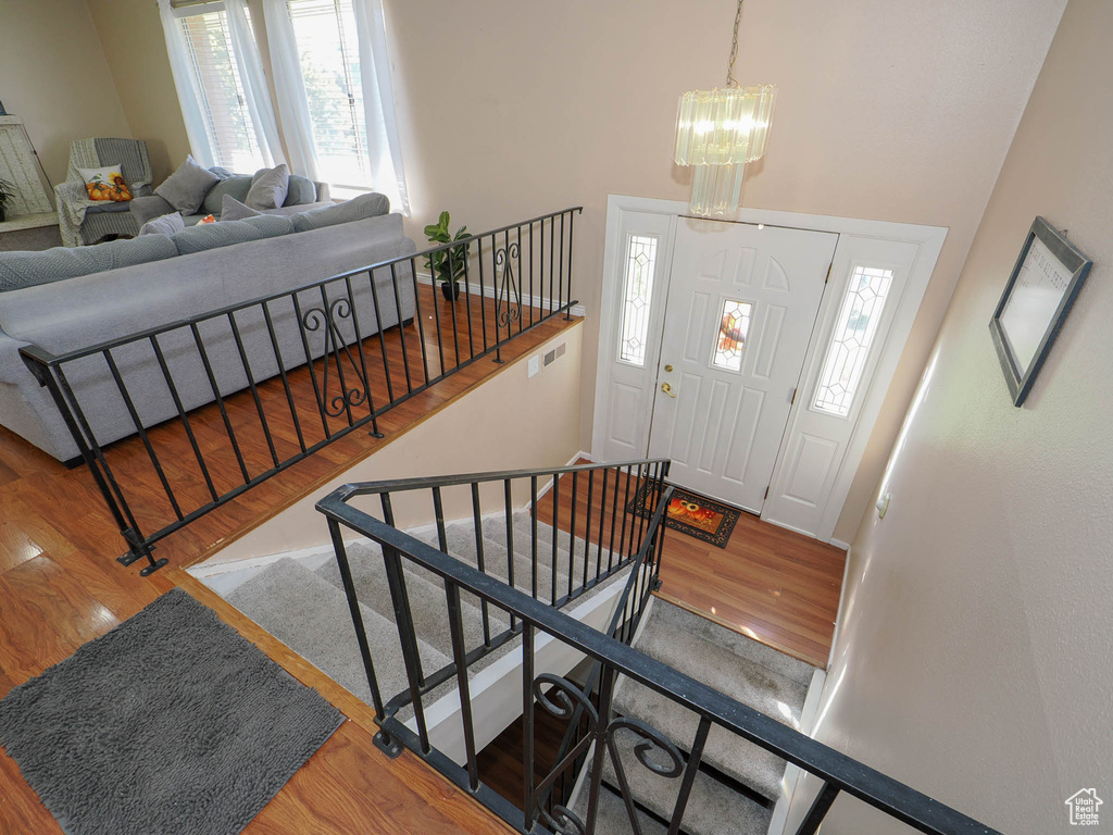 Entryway with a high ceiling, wood-type flooring, and an inviting chandelier