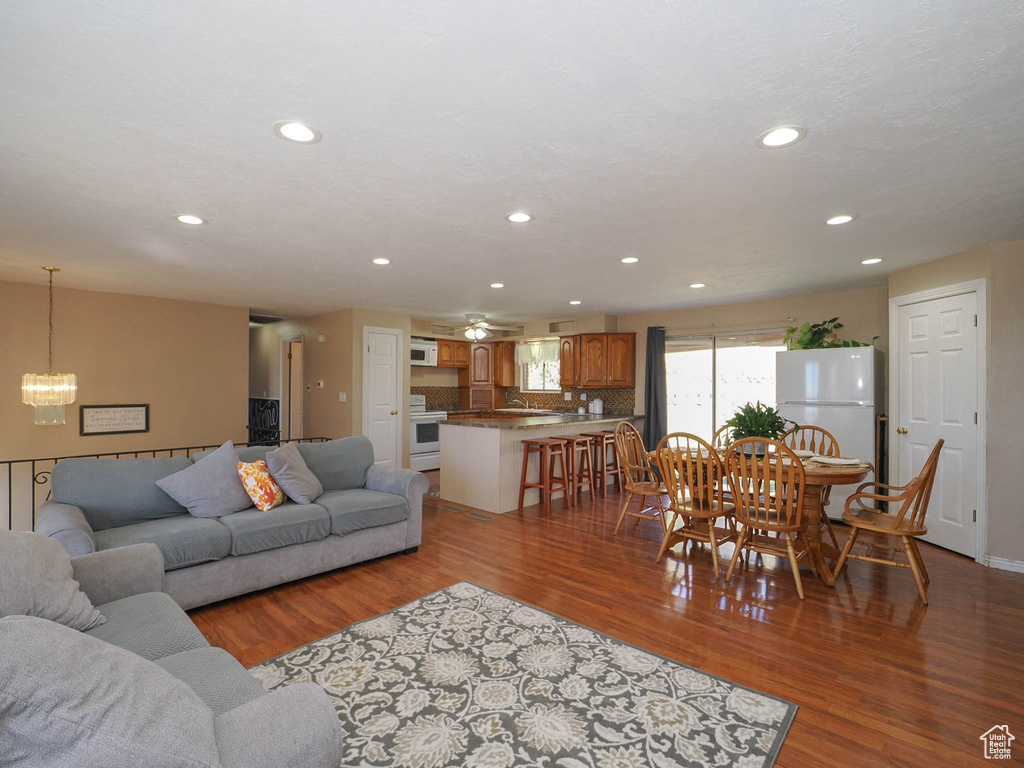 Living room featuring ceiling fan with notable chandelier and light hardwood / wood-style flooring