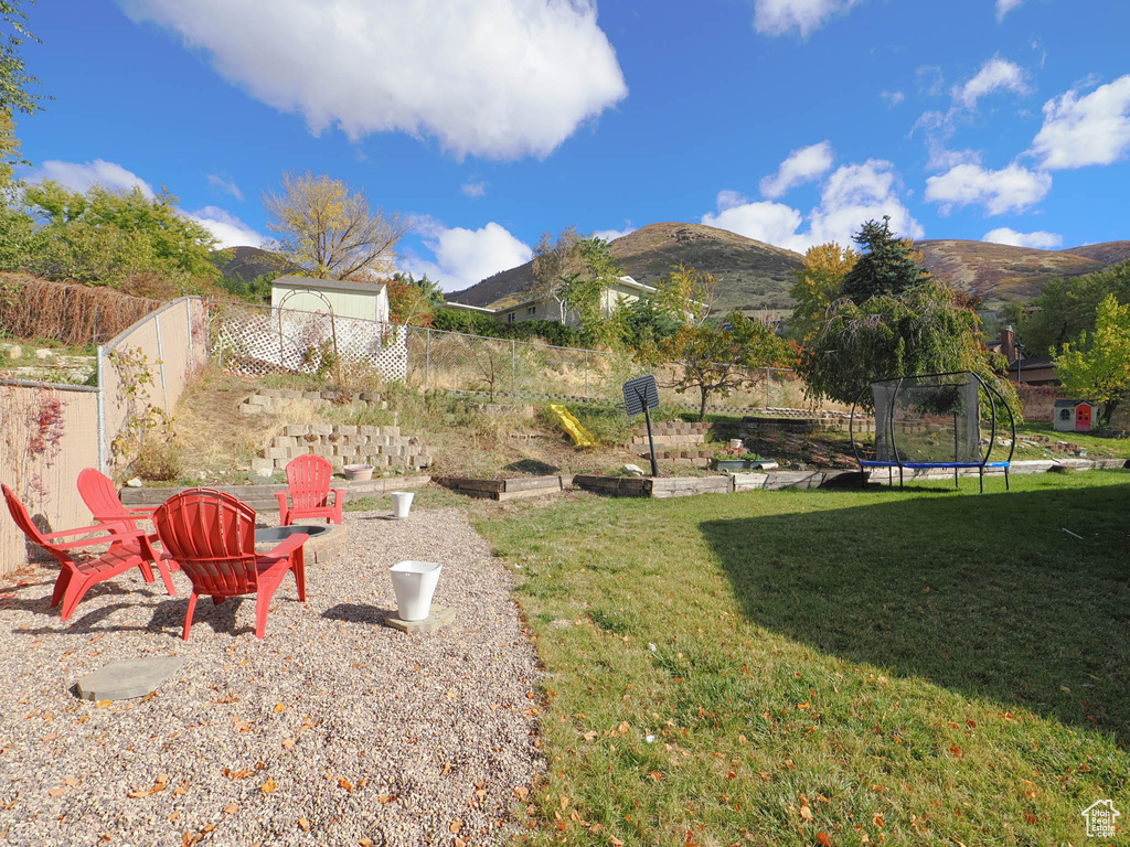 View of yard with a mountain view, an outdoor fire pit, and a trampoline