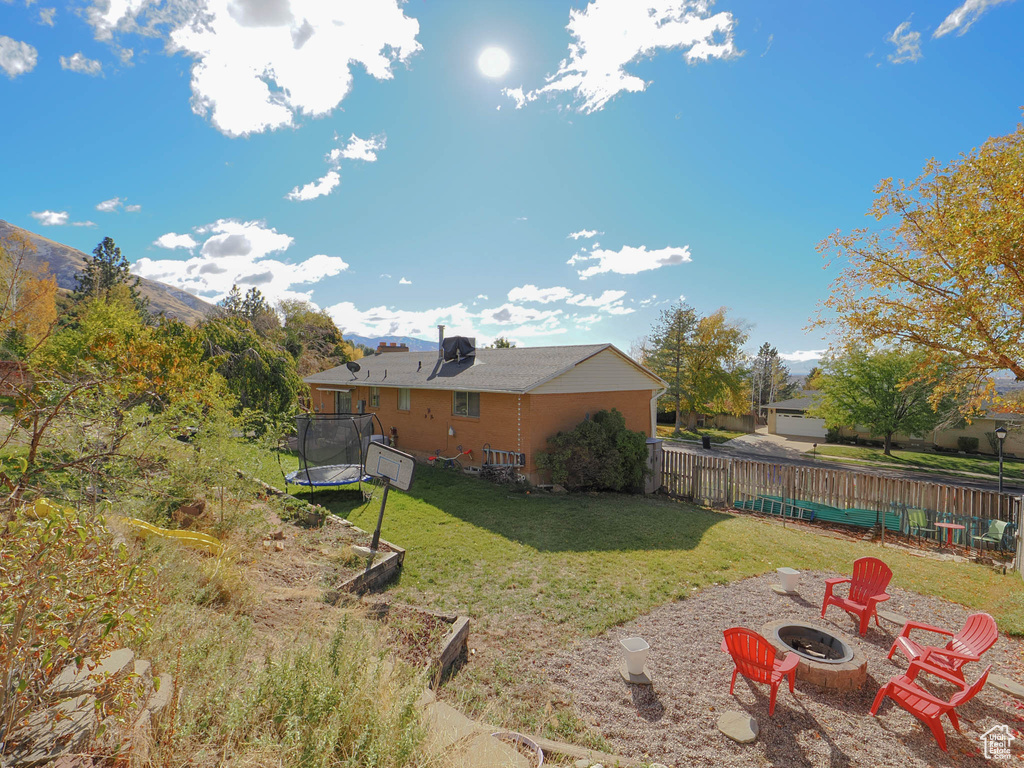 View of yard with a mountain view, a trampoline, and an outdoor fire pit