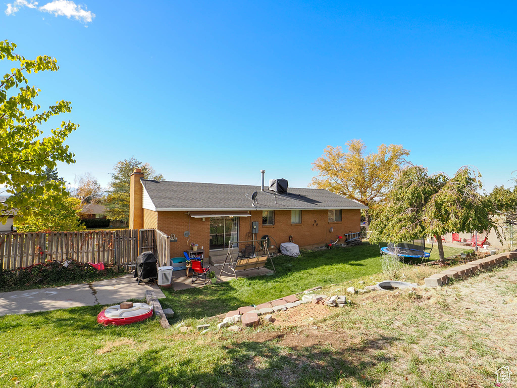 Rear view of house featuring a lawn, a patio area, and a trampoline