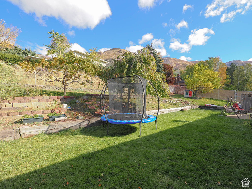 View of yard featuring a trampoline and a mountain view