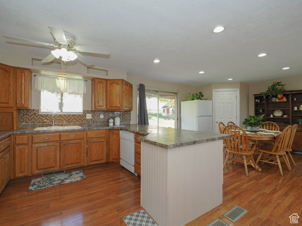 Kitchen featuring a wealth of natural light, light wood-type flooring, white appliances, and sink