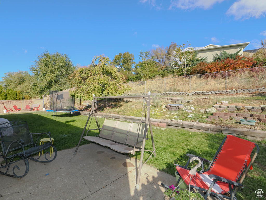 View of yard featuring a trampoline and a patio area