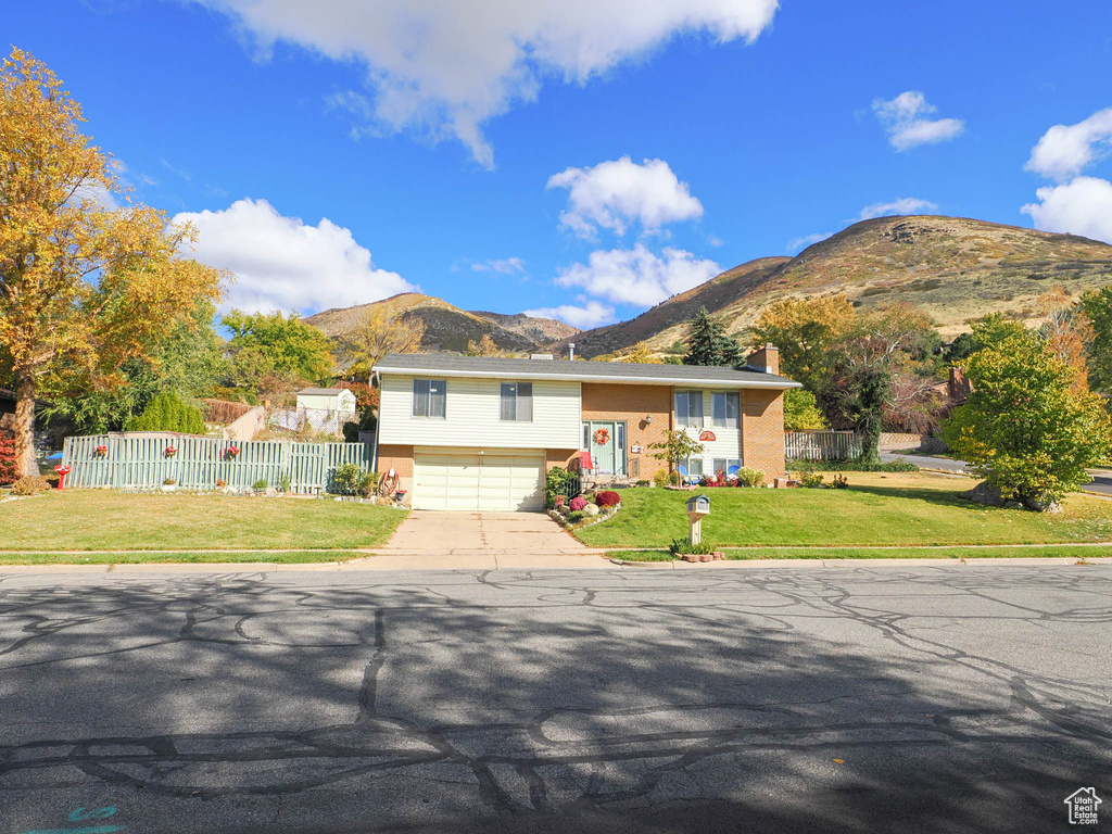 View of front facade featuring a garage, a front yard, and a mountain view