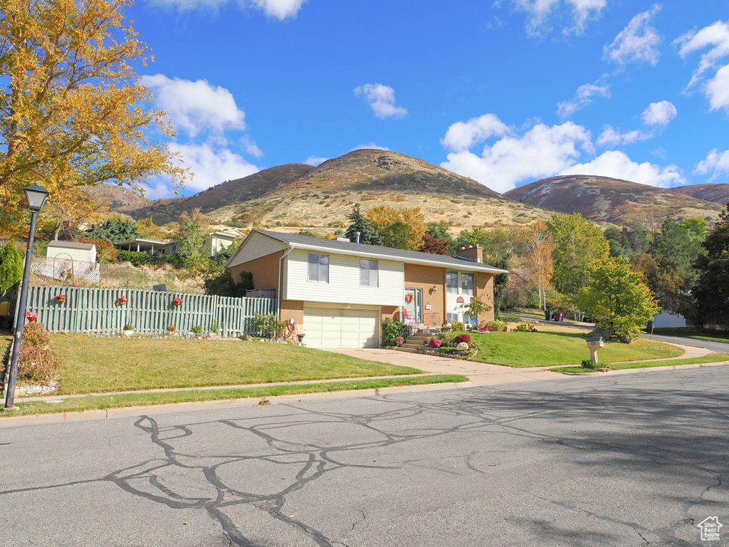 View of front of house with a mountain view, a garage, and a front yard