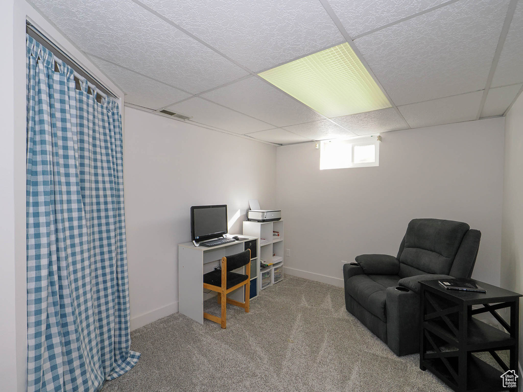 Interior space with a paneled ceiling and light colored carpet