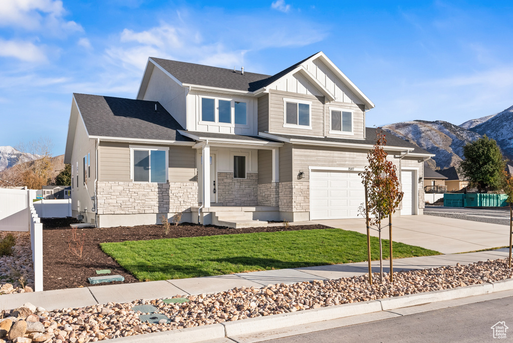 Craftsman-style home featuring a mountain view, a front lawn, and a garage