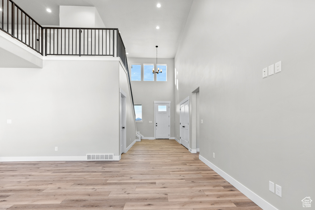 Entryway with a towering ceiling, light hardwood / wood-style floors, and an inviting chandelier