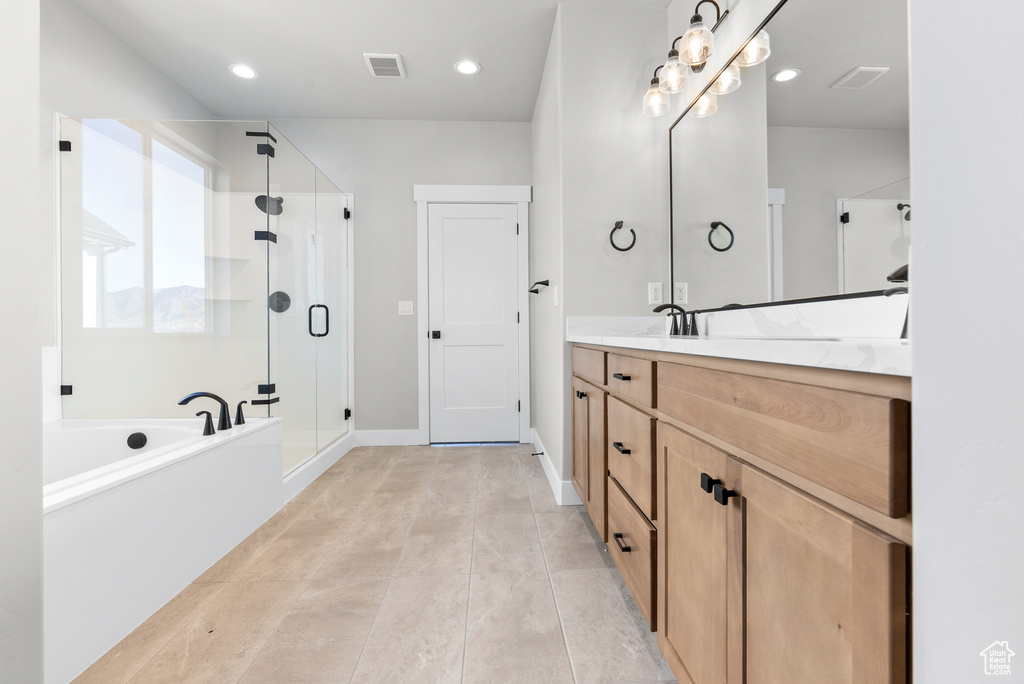 Bathroom featuring tile patterned flooring, shower with separate bathtub, and vanity