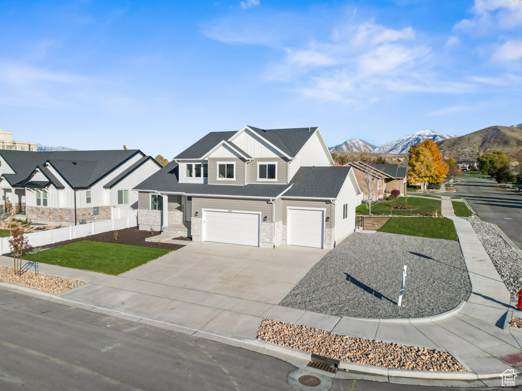 View of front of property featuring a mountain view, a front lawn, and a garage