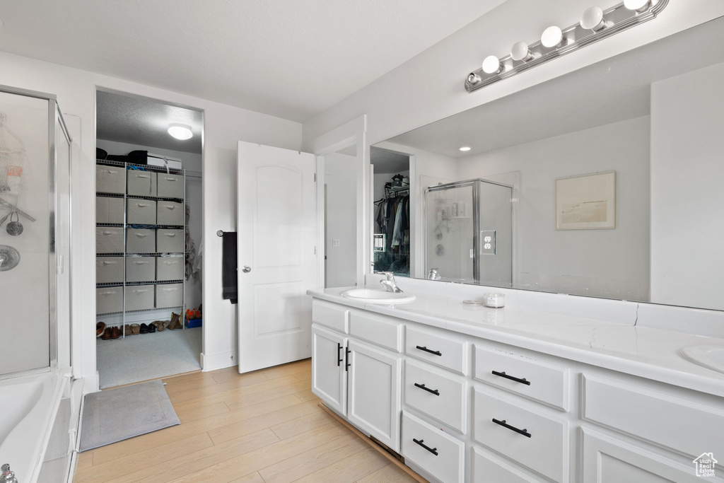 Bathroom featuring shower with separate bathtub, vanity, and hardwood / wood-style flooring