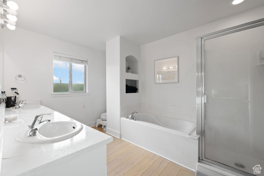 Full bathroom with hardwood / wood-style floors, vanity, toilet, and independent shower and bath